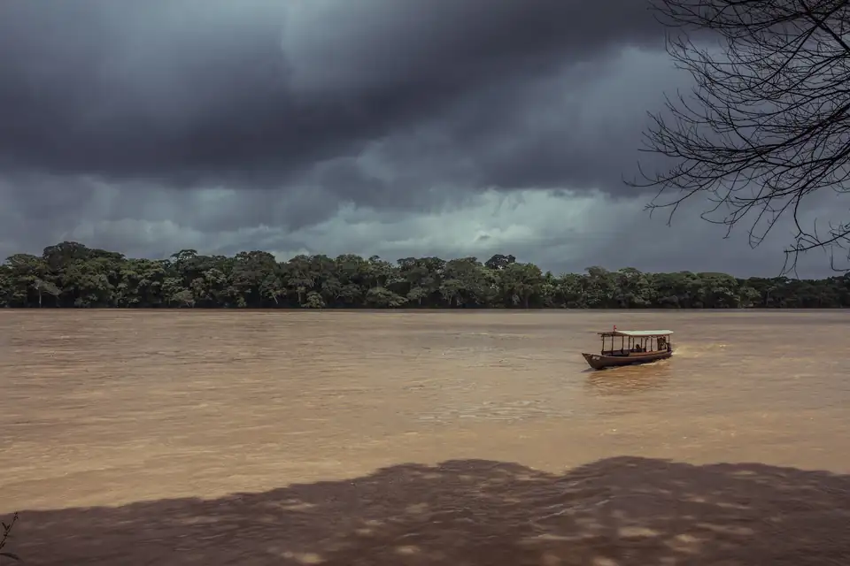 A boat on a wide river under a stormy sky