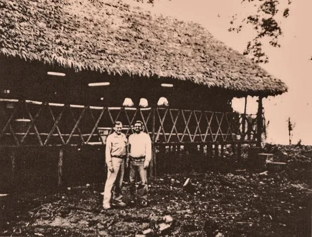 William Duellman and José Koechlin in front of a thatched building in Madre de Dios, 1986